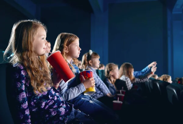 Smiling young spectators eating popcorn and watching cartoon in cinema. — Stock Photo, Image