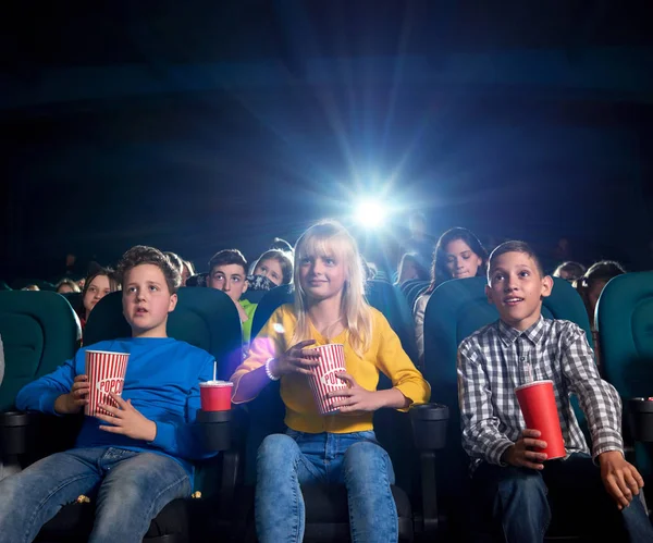 Jóvenes viendo películas y comiendo bocadillos en el cine . — Foto de Stock