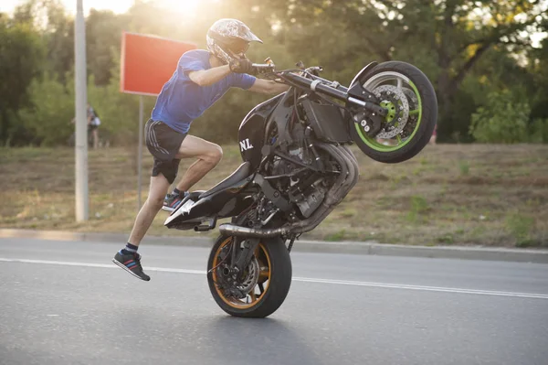 Vue latérale du motard en mouvement sur une roue . — Photo
