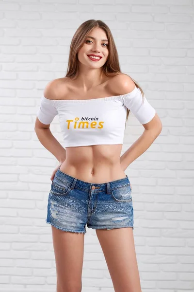 Modello allegro in pantaloncini di jeans e crop top bianco in posa con le mani sulle cosce — Foto Stock