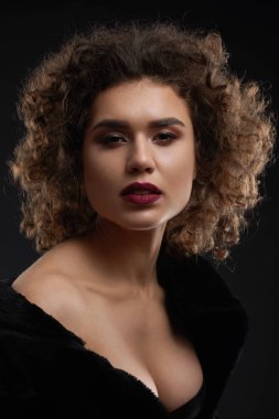 Seksi kıvırcık kadın stüdyoda poz.