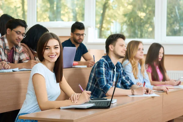 Giovane studente guardando la fotocamera seduta nell'università . — Foto Stock