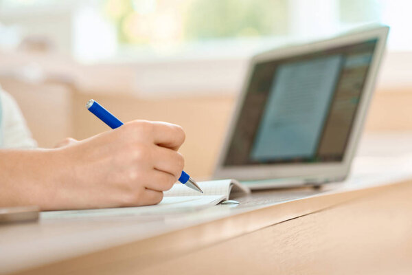 Students hand keeping a pen and writing in notebook.