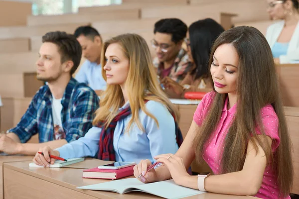 Estudiantes sentados en mesas de madera en el aula . — Foto de Stock