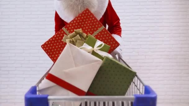 Senior Santa Claus empujando carrito de compras lleno de cajas de regalo — Vídeos de Stock