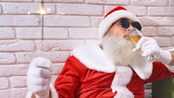 Kerstman in zonnebril champagne drinken en het houden van sterretjes — Stockvideo