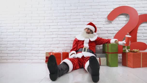 Starý muž v kostýmu Santa sedí ve studiu s dárkovými krabicemi — Stock video