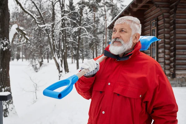 Чоловік у червоній куртці зі сніжною лопатою на плечі . — стокове фото