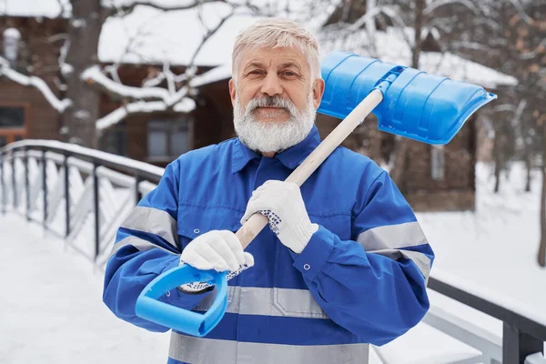 Прибиральник в робочому комбінезоні з лопатою на зимовому подвір'ї . — стокове фото