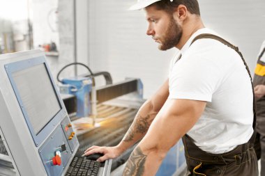 Üniformalı ve kasklı genç adam ekipmanla çalışıyor.