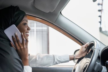 Siyah tesettürlü güzel bir kadın arabada telefonla konuşuyor.