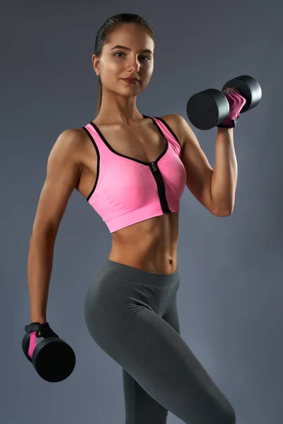 Front view of happy athletic female lifting heavy dumbbells — Stockfoto