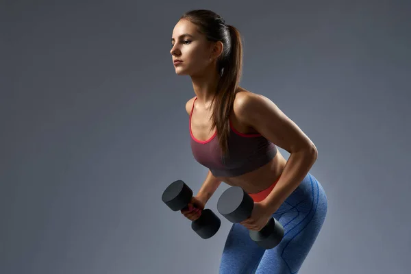 Attractive confident fitness girl pumping up muscles biceps — Stockfoto