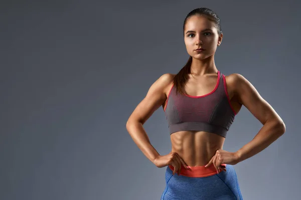 Portrait of slim female posing at camera in sportswear — Stockfoto