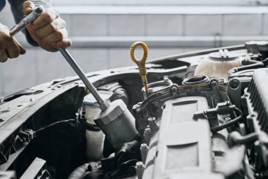 Erkeğin elleri, piston silindirini ingiliz anahtarıyla sıksın.