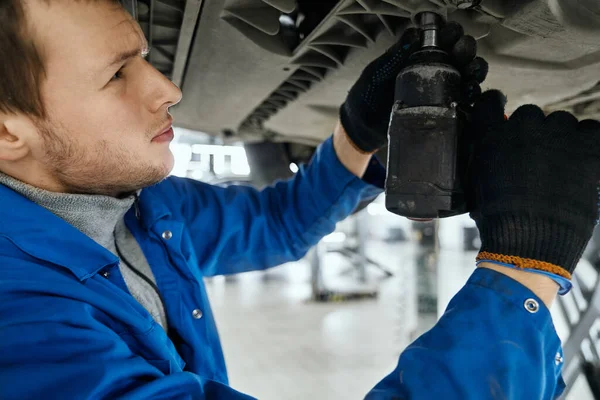 Nahaufnahme des Mechanikers zieht die Schrauben am Boden des Autos an — Stockfoto