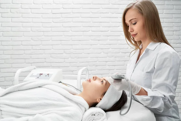 Esteticista haciendo ultrasonido facial al cliente . — Foto de Stock