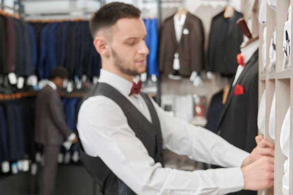 Jovem com barba escolhendo camisa na boutique . — Fotografia de Stock