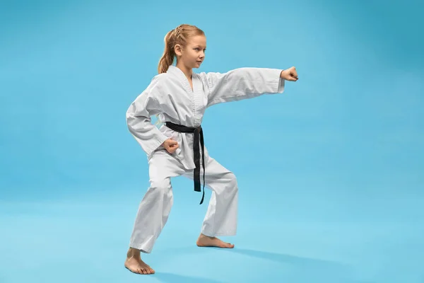 Girl in kimono standing in stance and punching with hand. — Stock Photo, Image