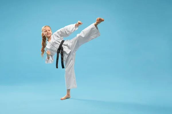 Karate menina em kimono branco praticando artes marciais . — Fotografia de Stock