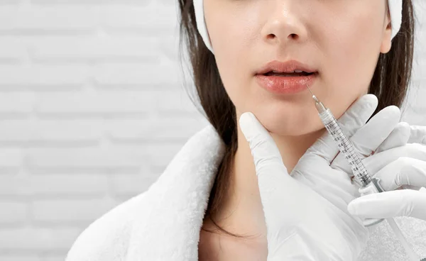 Brunette receiving botox with syringe in lips. Stock Image