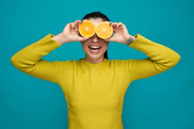 Portakal dilimleri tutan, dürbün kullanan oyuncu kız..