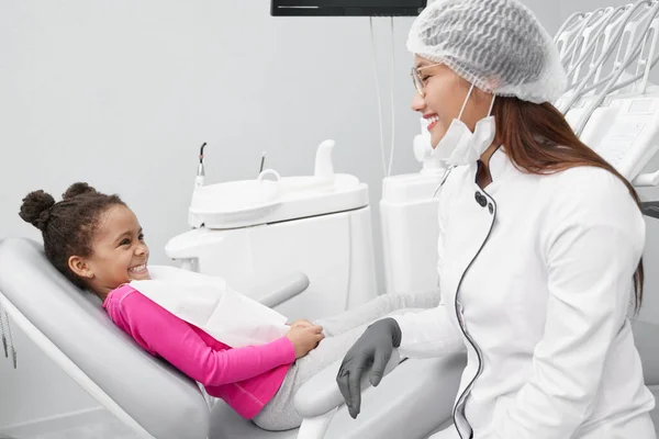 Chica mirando al dentista femenino y riendo en la clínica — Foto de Stock