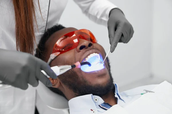 Klinikte koruyucu gözlüklü bir adam dişçi koltuğunda yatıyor. — Stok fotoğraf