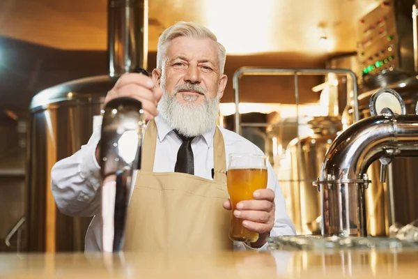 Anciano barman de pie en el mostrador del bar con vaso de cerveza . —  Fotos de Stock