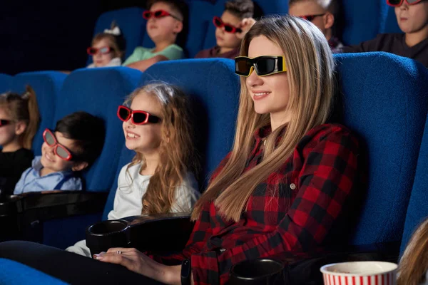 Sonriente madre sentada con su hijita en el cine — Foto de Stock