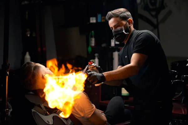 Portrait of barber giving hair fire treatment to his client — Stock Photo, Image