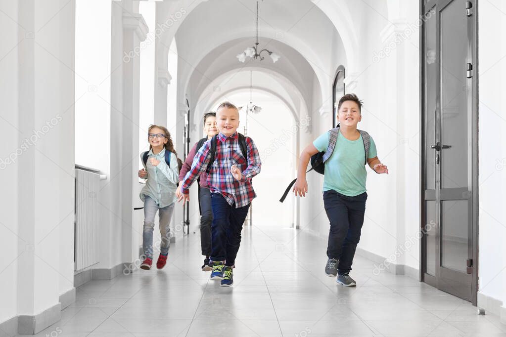 Happy pupils running forward on corridor of school.