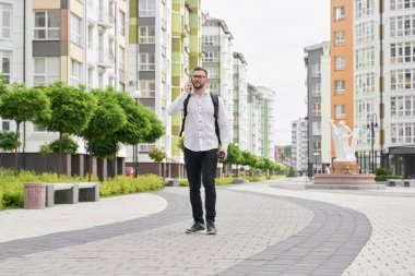 Genç adam telefonla konuşuyor, sokakta yürüyor..