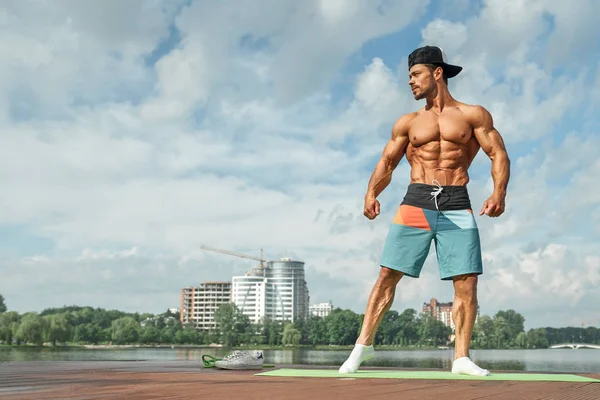 Deportista muscular con torso pesado posando cerca del lago . — Foto de Stock