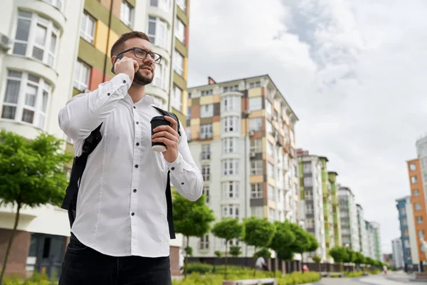 Hombre de pie, hablando por teléfono, mirando nuevos edificios . — Foto de Stock