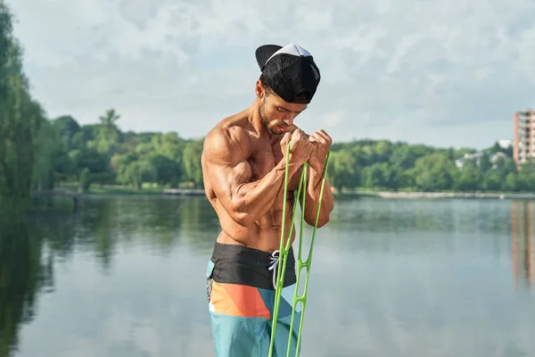 Esportista com treinamento de corpo muscular atlético perto do lago . Fotografia De Stock