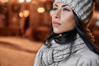 Sokakta örülmüş yün şapkalı ve atkılı bir kadın..