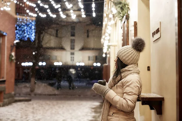 Menina de pé na rua com xícara de café na noite de inverno . — Fotografia de Stock