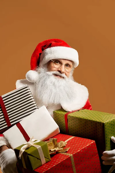 Brodaty Święty Mikołaj pozowanie w studio z mnóstwem prezentów — Zdjęcie stockowe