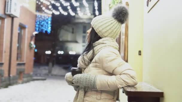 Dívka pije kávu opírající se o polici venku v zimě. — Stock video