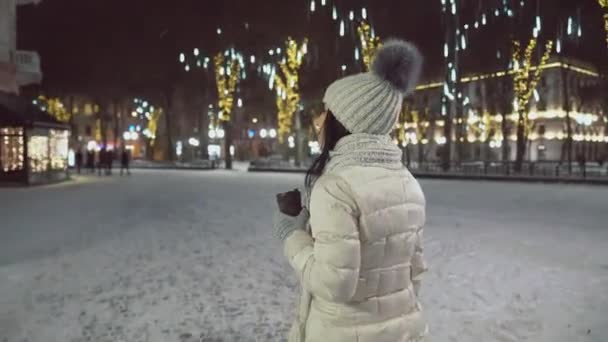 Model v zimním oblečení s šálkem kávy rozhlíží kolem. — Stock video