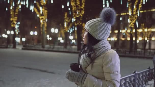 Κορίτσι με φλιτζάνι καφέ το βράδυ των Χριστουγέννων στο δρόμο. — Αρχείο Βίντεο