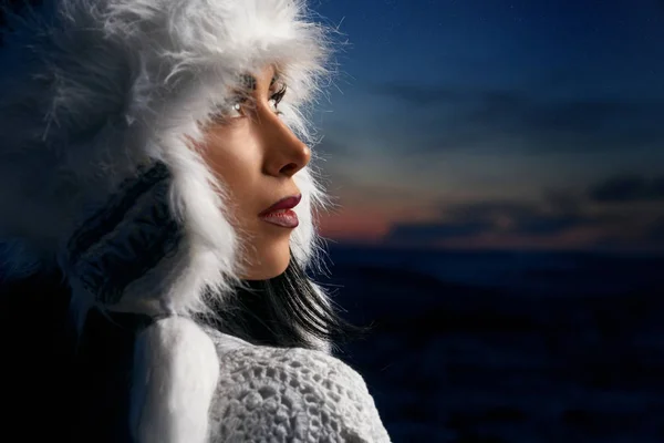 Μοντέλο το χειμώνα λευκό καπέλο στο φόντο του νυχτερινού ουρανού. — Φωτογραφία Αρχείου