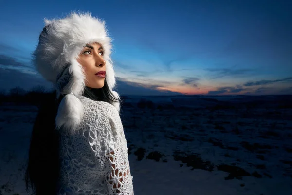 Chica en sombrero caliente blanco en el campo cubierto de nieve . —  Fotos de Stock