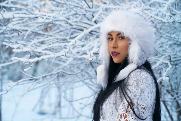 Menina em chapéu quente no fundo de árvores com neve . — Fotografia de Stock