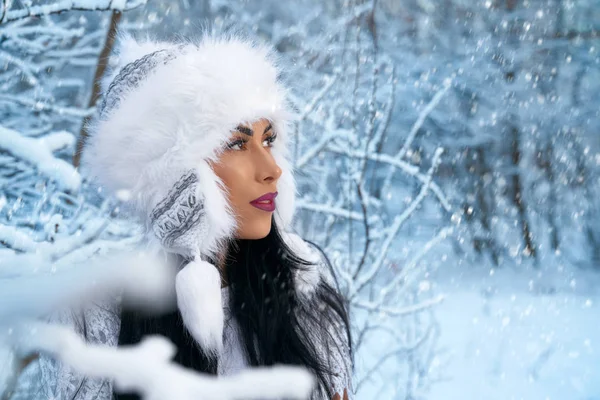 Menina no inverno chapéu branco na floresta com neve perto de árvores . — Fotografia de Stock