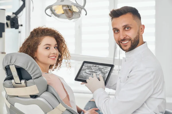 Médico y mujer posando sentados en consultorio dental —  Fotos de Stock