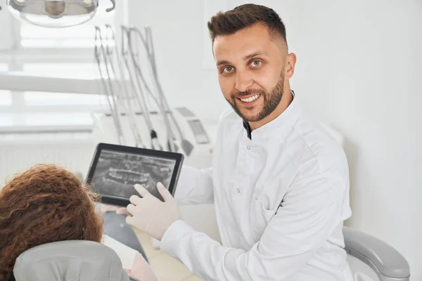 Pozytywny mężczyzna dentysta pozowanie podczas konsultacji z pacjentką — Zdjęcie stockowe