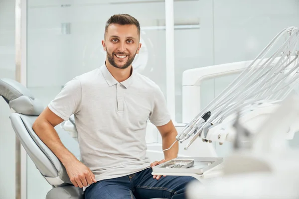 Dişçi koltuğunda oturan yakışıklı erkek hasta ön planda. — Stok fotoğraf