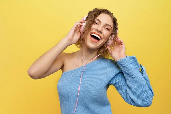Chica glamour escuchando música con auriculares rosados . — Foto de Stock